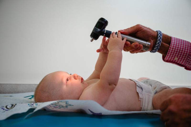 a doctors hand holding a light over a baby on a table