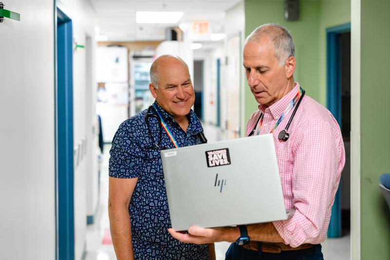 two older men doctors looking at a laptop together